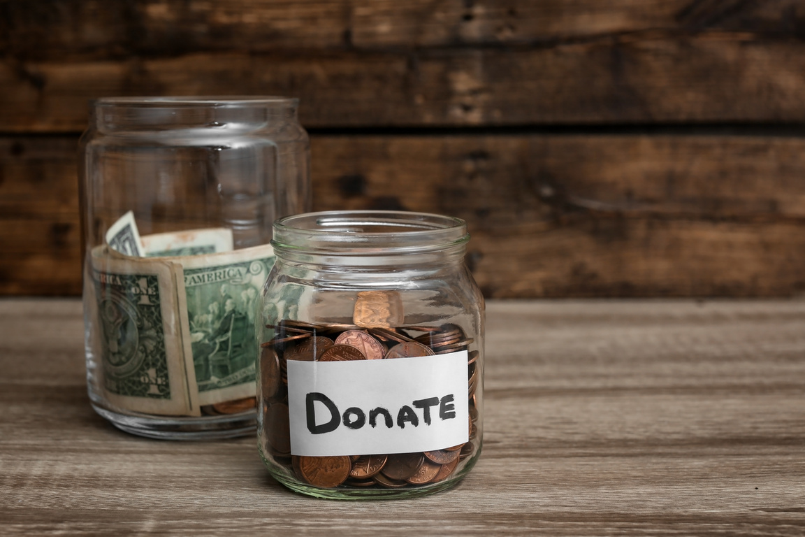 Donation Jars with Money on Table. Space for Text